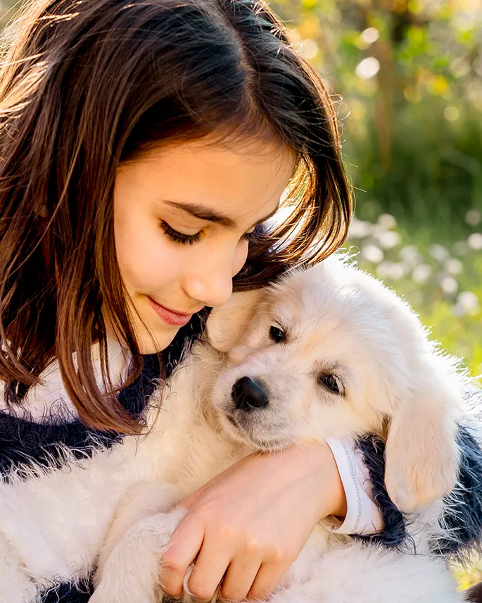 A girl hugging a fluffy golden puppy